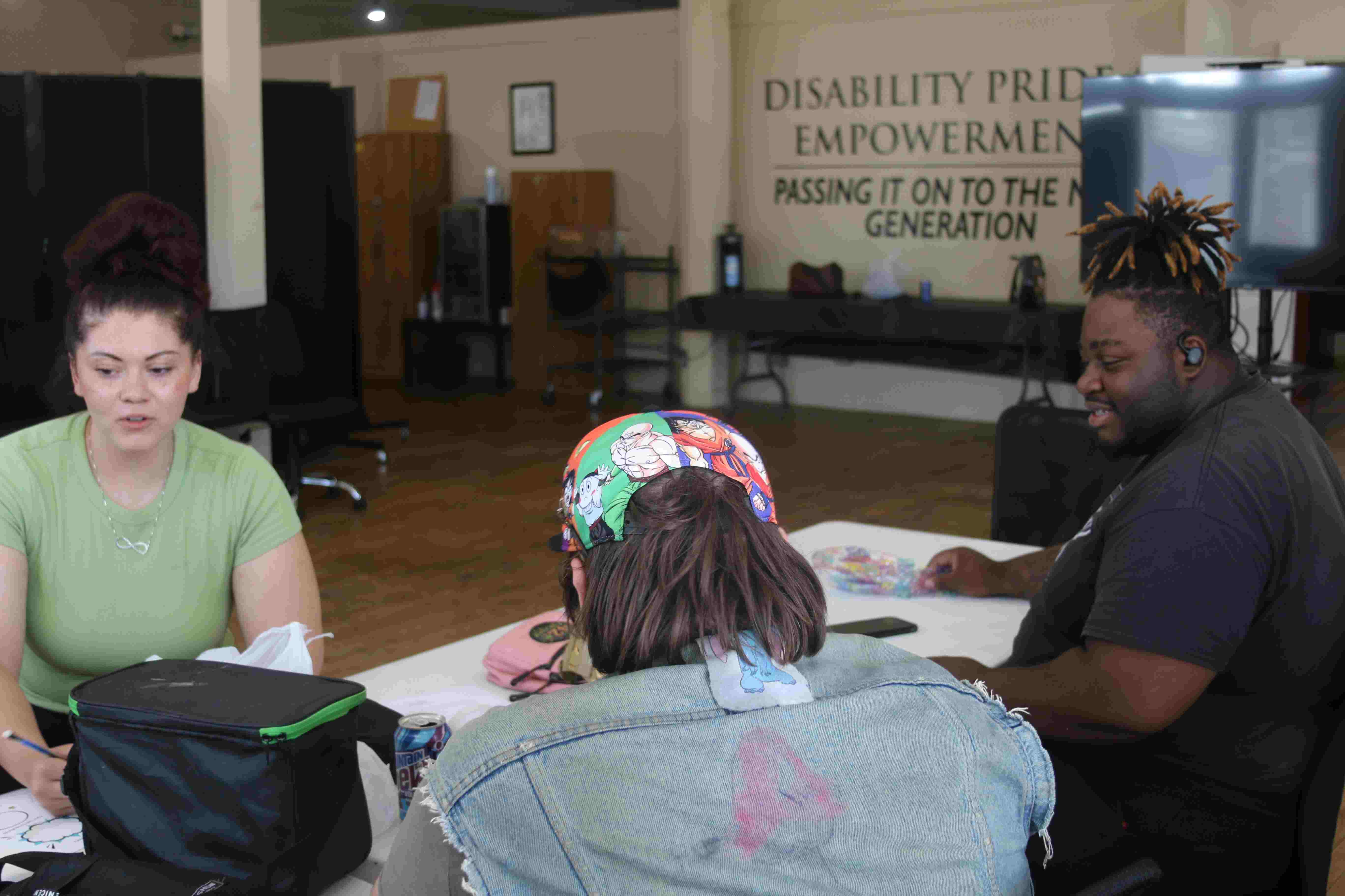 three people drawing on paper. they are seated at a white table.