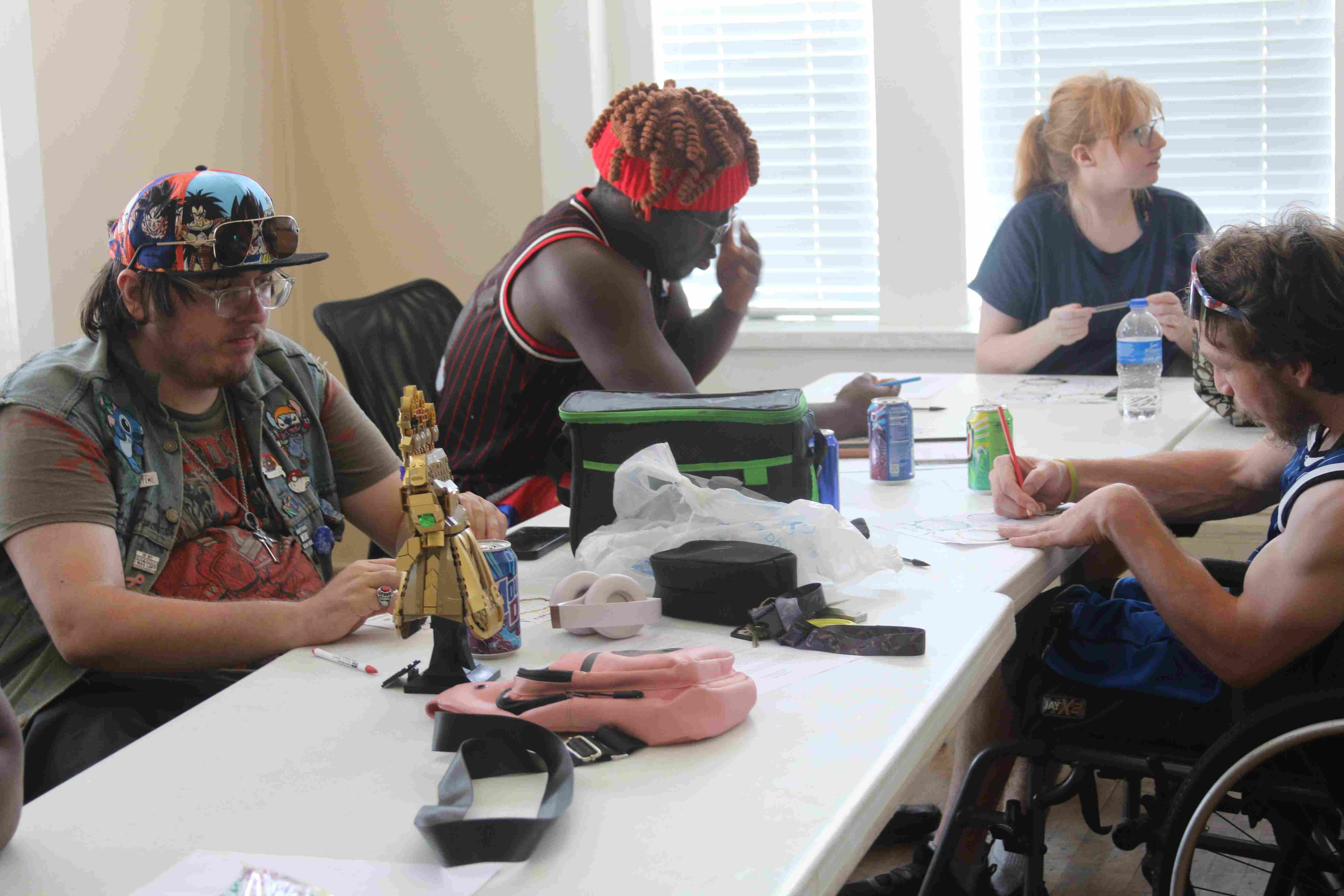four people at a table drawing on a piece of paper.